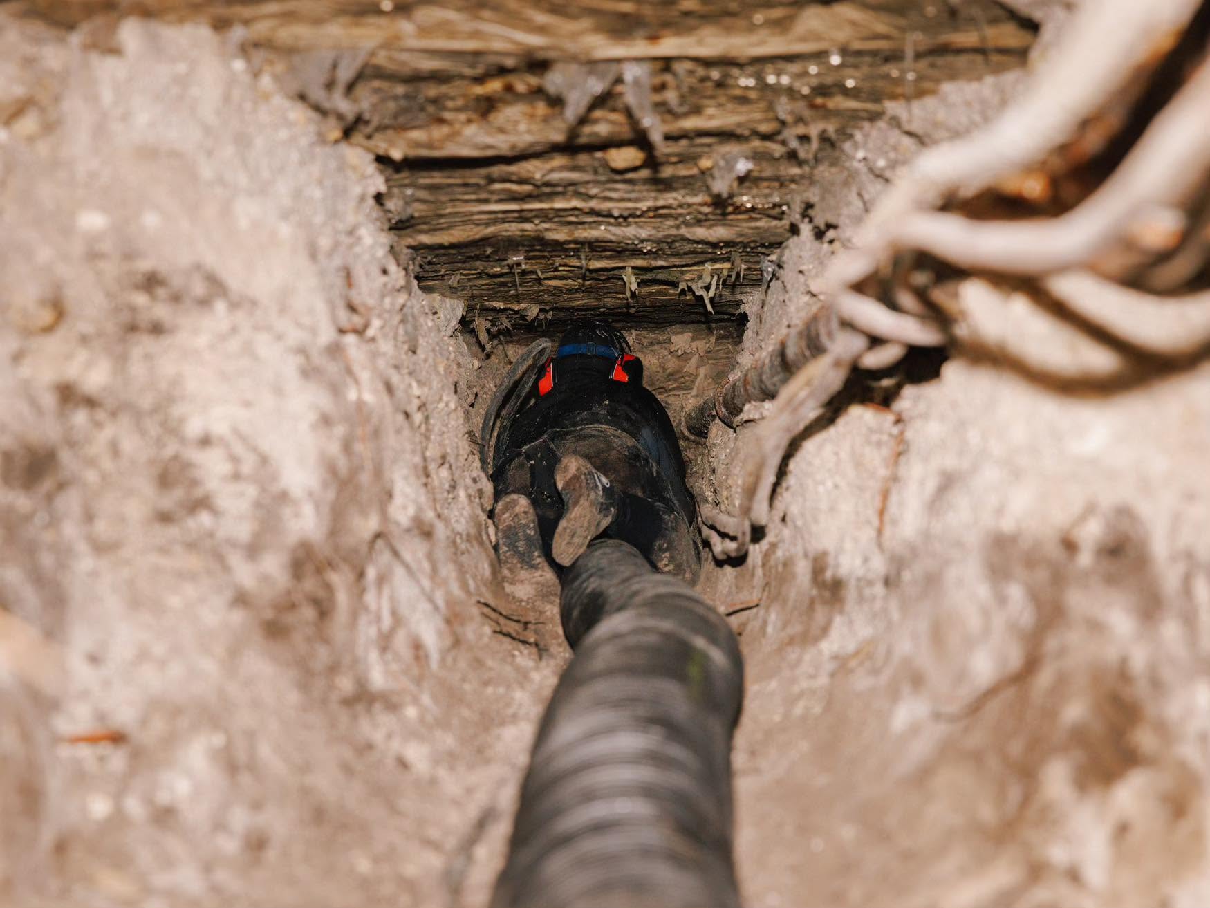 Crew member hydro-excavating a tunnel beneath a home
